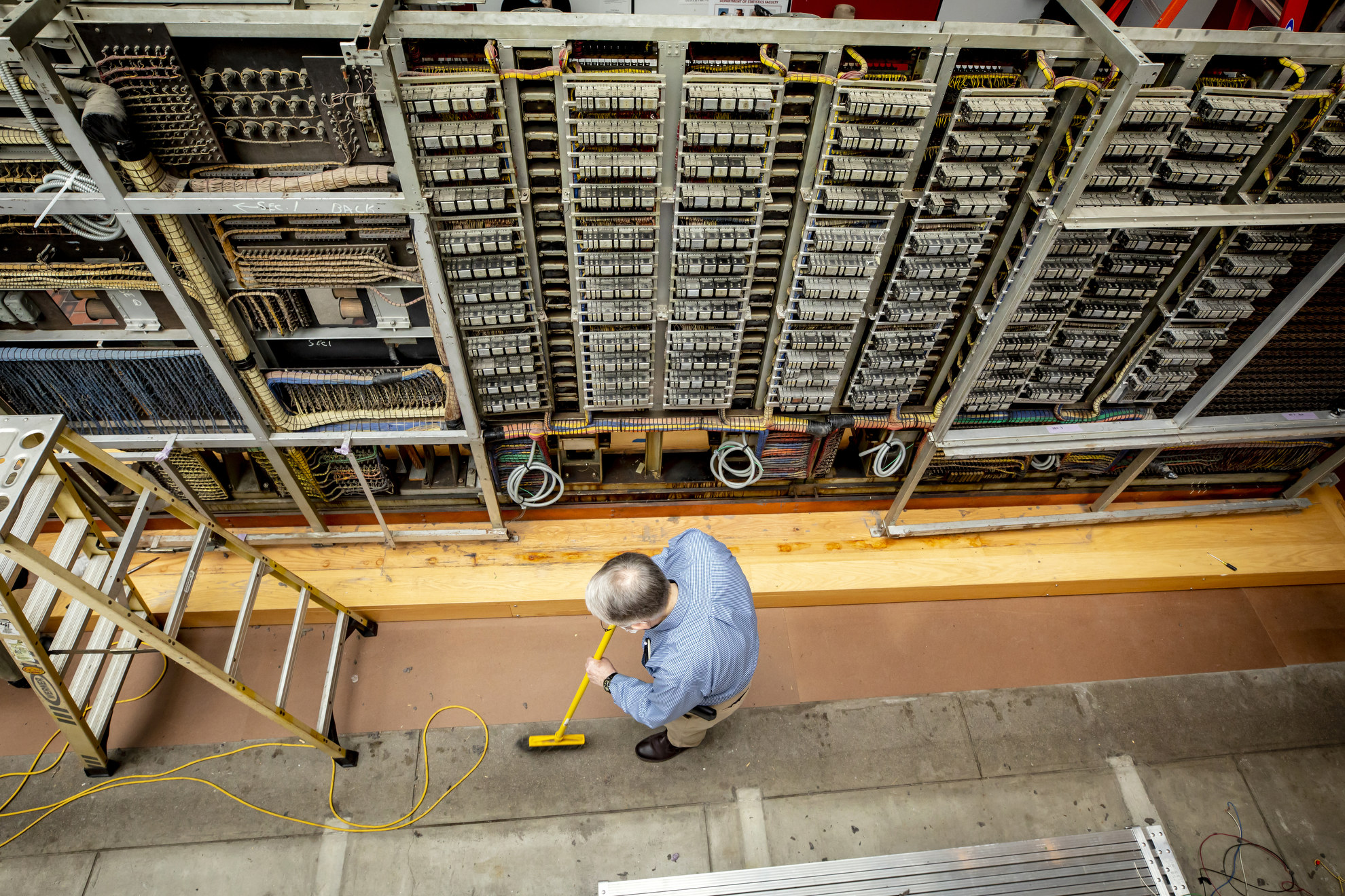 O.B. Hill Trucking and Rigging, of Natick, MA and the Collection of Historical Scientific Instruments at Harvard are dissembling the legendary Mark 1 computer at the Science Center and transporting it to the SEC where it will be reassembled. A man sweeps around the partially disassembled computer still at the Science Center.