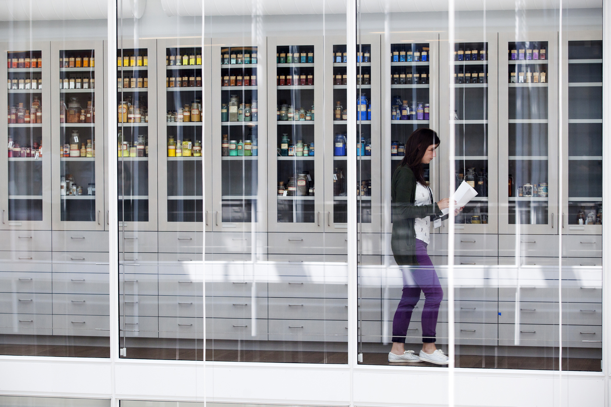 A woman walks past the pigment collection at Harvard Art Museums.