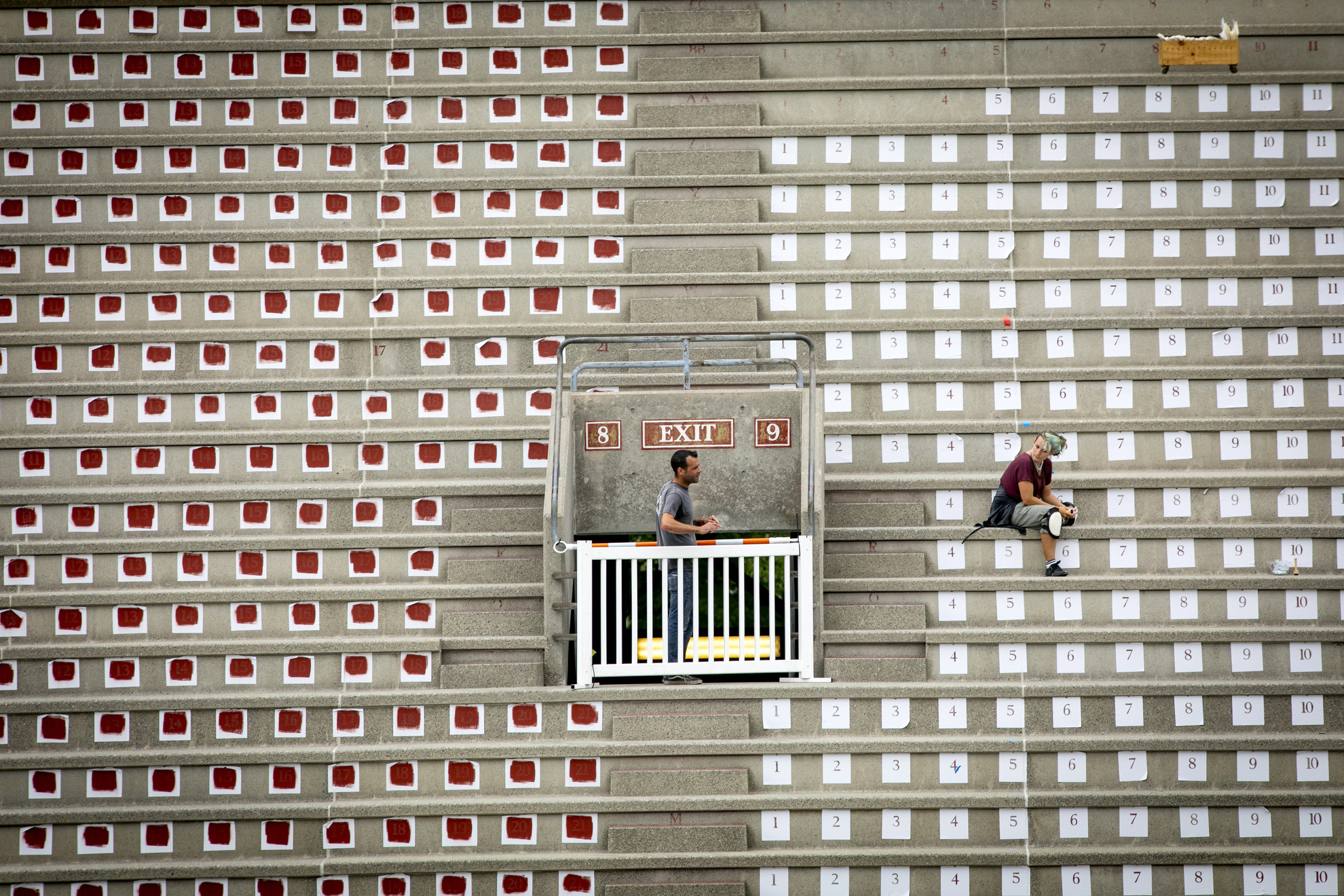 Melissa Dole re-letters the seat numbers in Harvard Stadium using stencils.