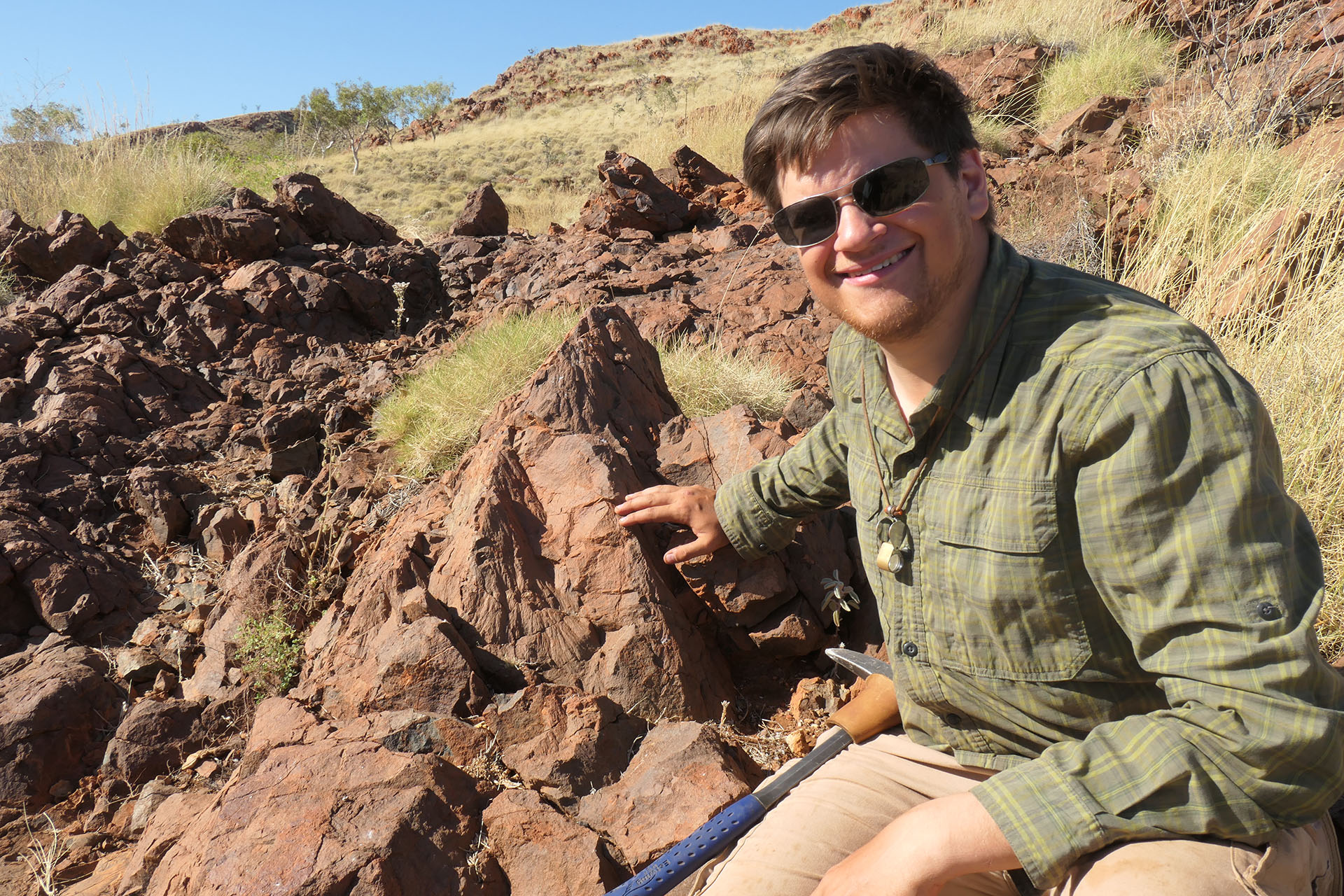 Alec Brenner with rock formations in the field.