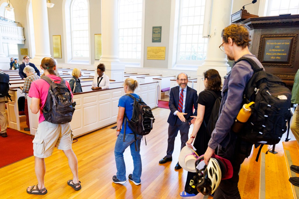 Harvard President Alan Garber shakes hands with attendees outside Appleton Chapel.