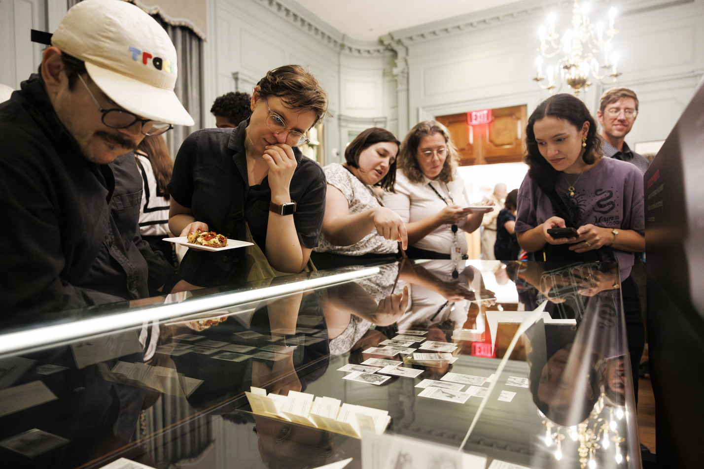 Attendees looking at drawings in one of the display cases.
