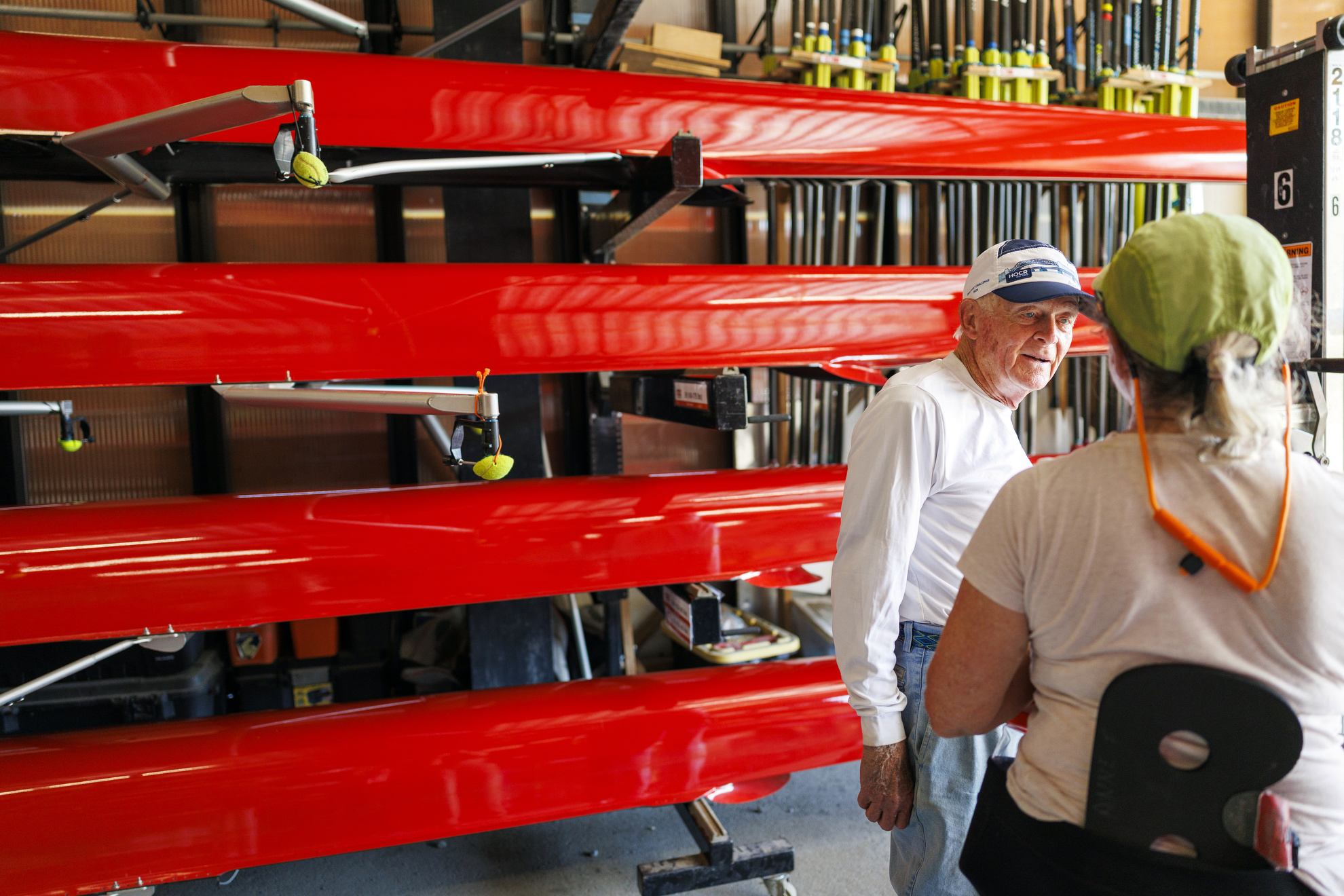 Bill Becklean, the 89-year-old coxswain for the Octo Eight, speaks with a fellow rower following a morning practice on the Charles River.