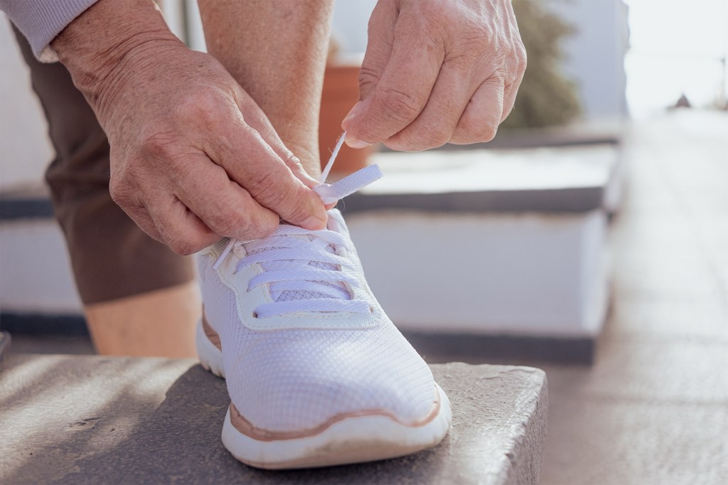 Close-up of woman's hands tying the laces of white sneakers.