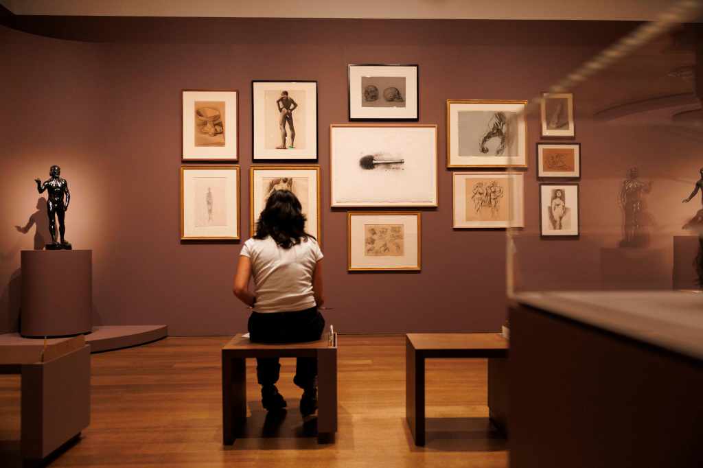 a woman sitting in front of a gallery wall