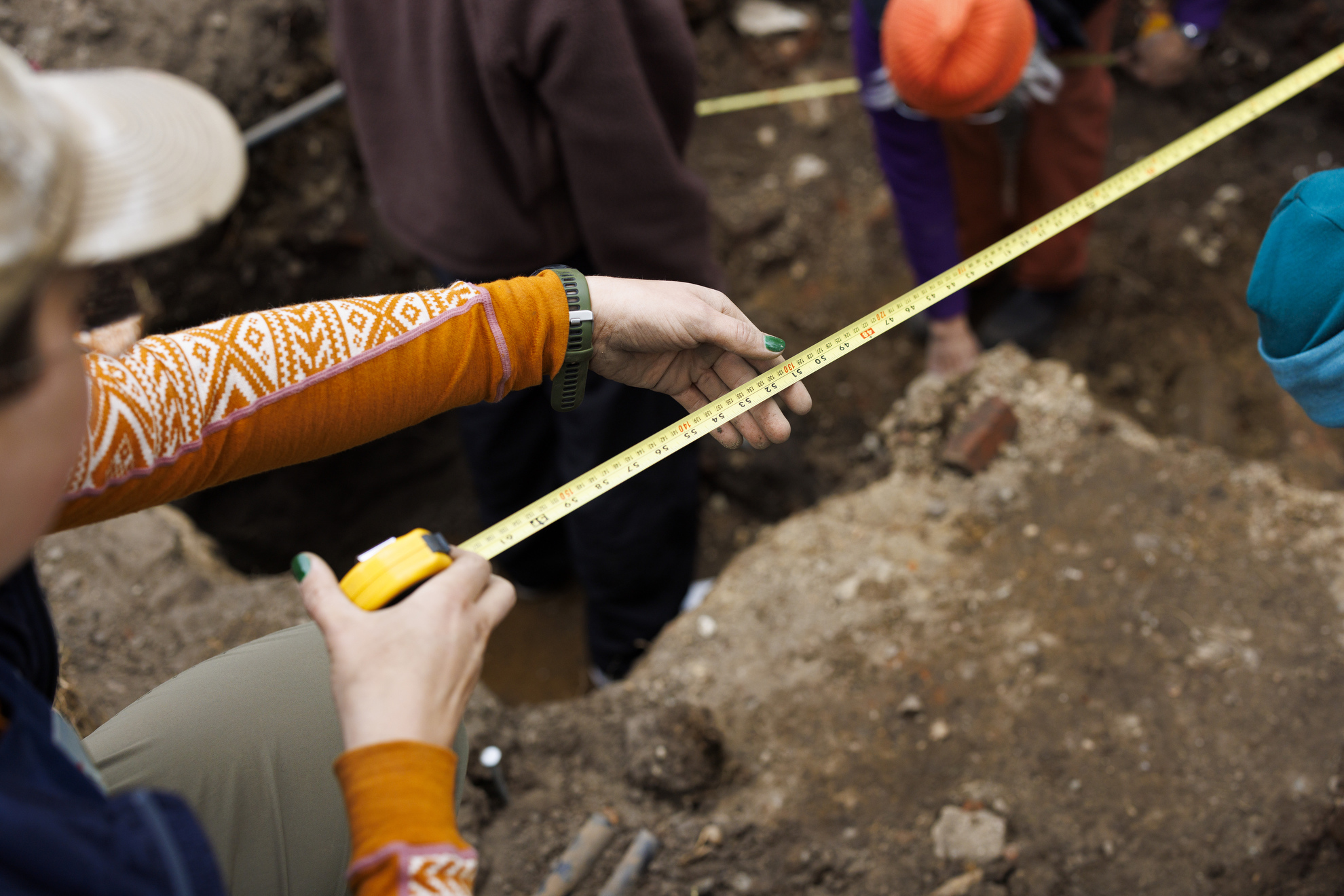 Emily Conlogue, a teaching fellow and PhD student in Archaeology, measures a section of the dig site.
