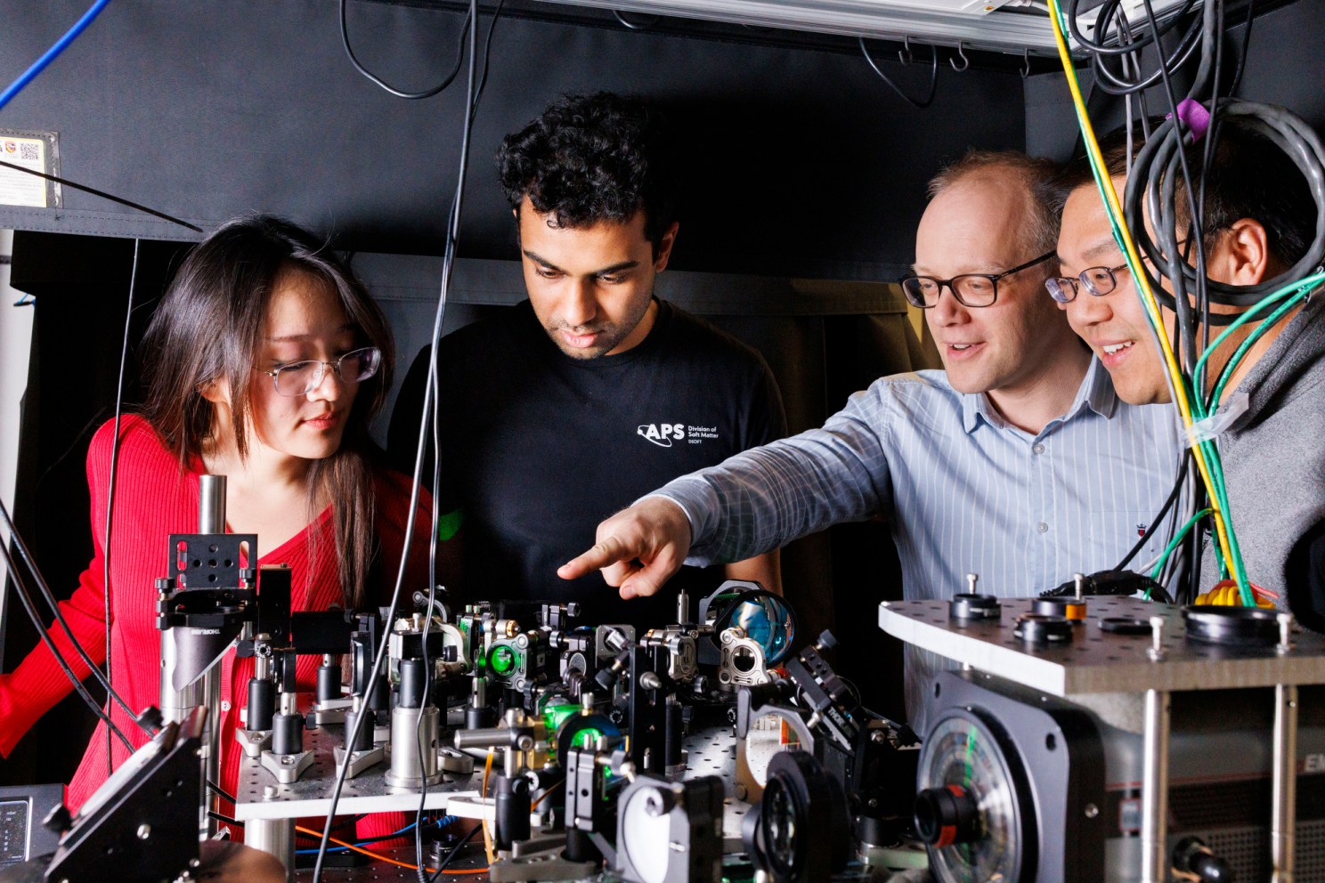 Chris Laumann (second from right), an associate professor of Physics at Boston University, points to a research instrument as Graduate students Esther Wang and Srinivas Mandyam, and Norman Yao.